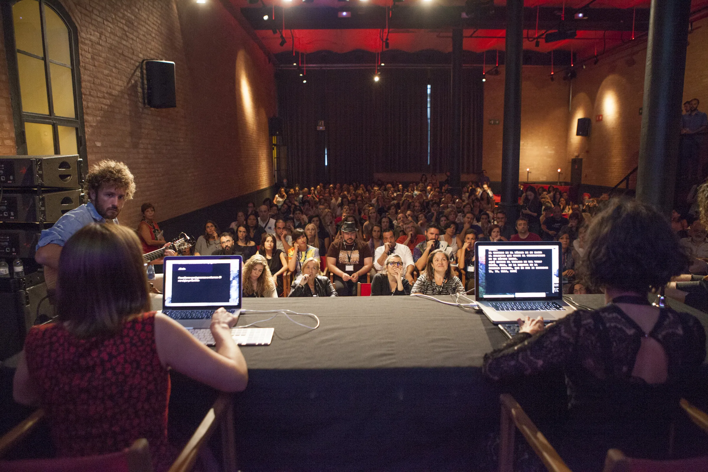 Two writers at keyboards facing a full audience during the Writing Slam final at the Antiga Fàbrica Estrella Damm, Barcelona, 2016