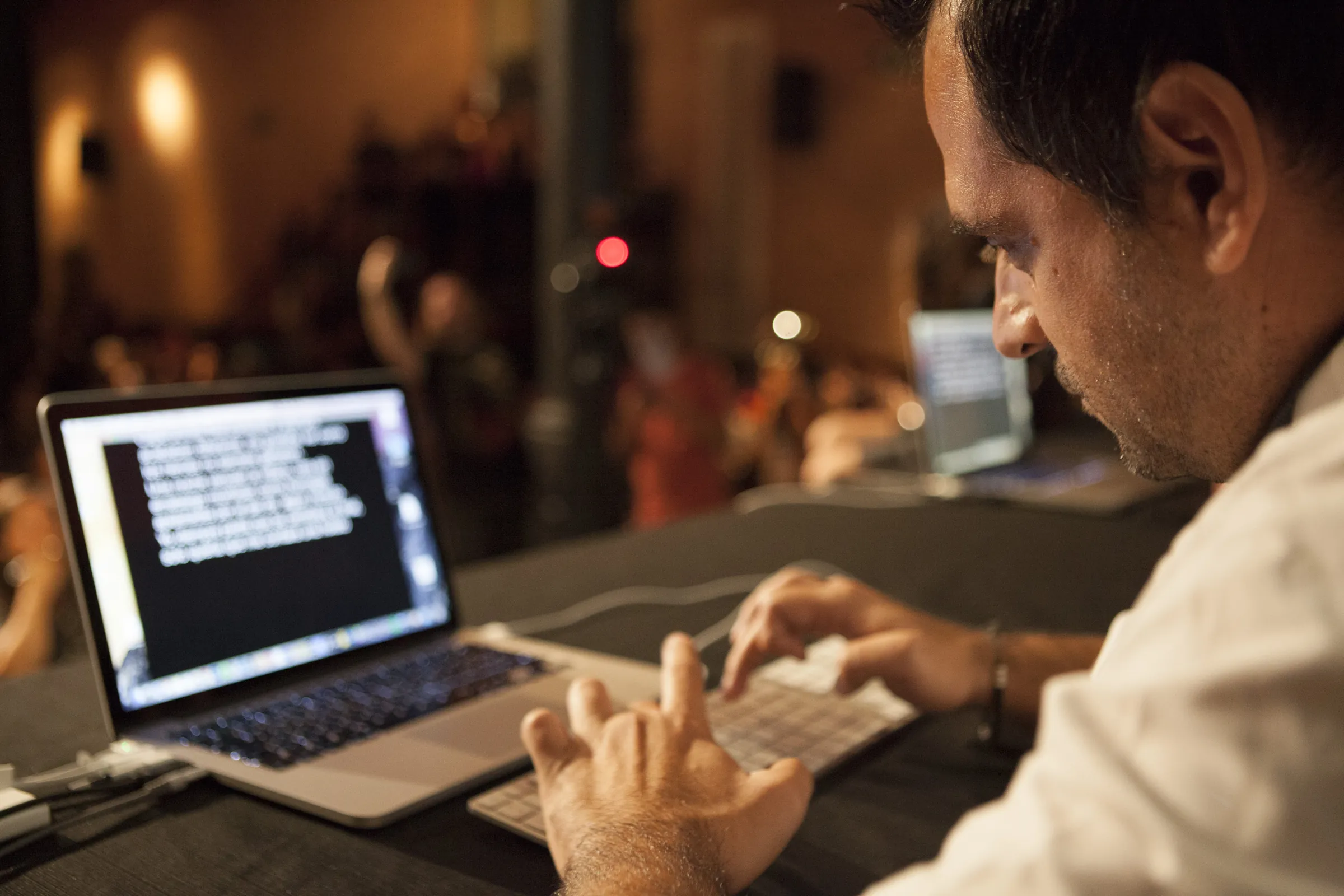 A writer typing at a laptop with the audience reading behind him, Antiga Fabrica Estrella Damm, Barcelona, 2016